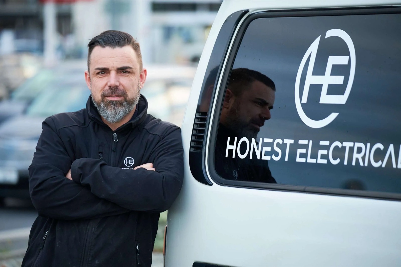 Tim, owner of Honest Electrical, standing next to the Honest Electrical van in Dunedin